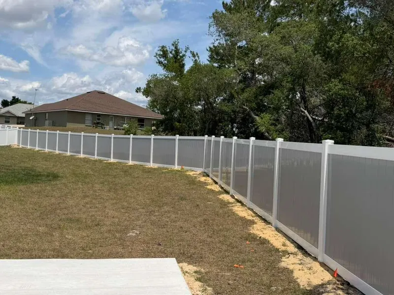 White vinyl privacy fence along a paved patio